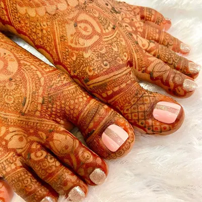 Beautiful toe nails to match a beautiful bride. This pedicure was designed to complement her bridal henna, featuring a soft pink base with a minimalist gold stripe and glitter accents.