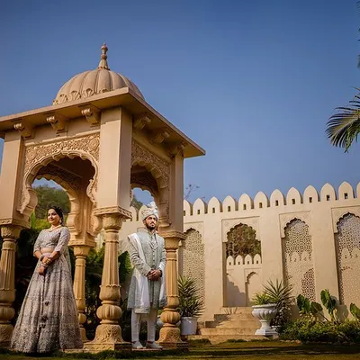 A majestic portrait of Yash and Priyanshi in traditional Indian wear, standing beside a beautiful stone cenotaph. This shot captures the essence of royal Rajasthani architecture and elegance.