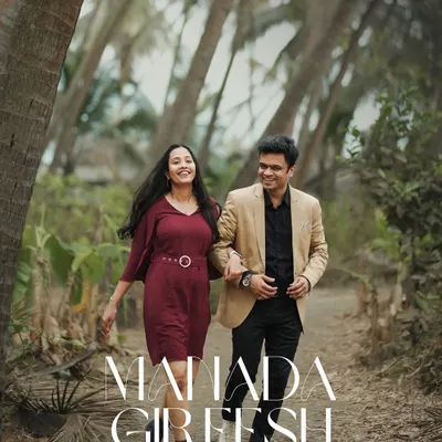 A happy, natural shot of a couple walking arm-in-arm through a tree-lined path. This kind of casual pre-wedding photography captures the couple's easy-going chemistry.