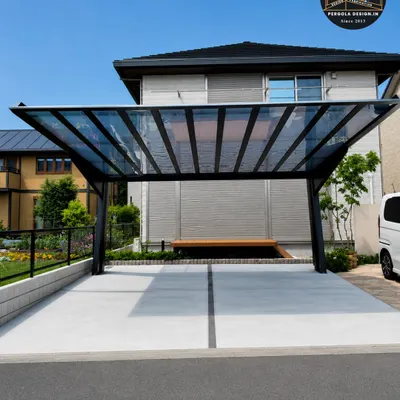 This freestanding carport features a sleek, angled design with a toughened glass roof. The black steel frame provides strong support while maintaining a minimalist profile, offering weatherproof protection without blocking sunlight or the view of the sky.