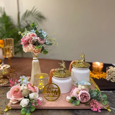 A beautiful Diwali hamper featuring a marble-finish tray, elegant deer-topped jars, and a floral bouquet. This set is designed to bring a touch of modern elegance to your festive gifting.