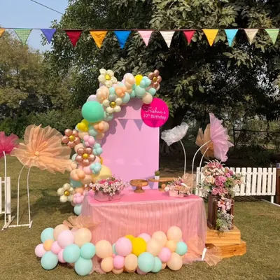 A beautiful pastel-themed birthday setup featuring a balloon arch and a dedicated cake table, ready for a special celebration.