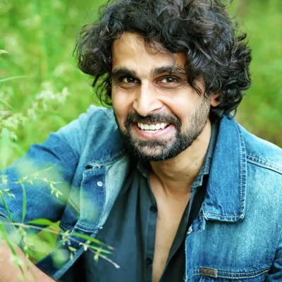 A genuine, heartfelt smile captured during an outdoor portrait session. I use the natural foliage as a soft frame to create a relaxed and engaging men's fashion portrait.