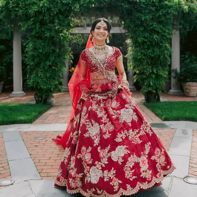 A classic red bridal lehenga never goes out of style. Here, the intricate silver and gold floral embroidery by Dolly J Studio creates a look of pure elegance.
