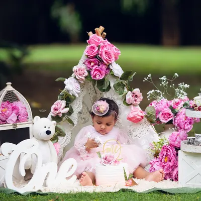 A beautiful first birthday cake smash in the park. This outdoor setup with a lace teepee and pink flowers creates a magical, bohemian vibe.