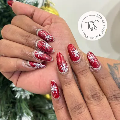 Get into the holiday spirit with these festive Christmas nails, featuring a bold red glitter base with hand-painted white snowflakes.