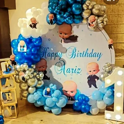 A Boss Baby theme is perfect for a little one turning one. This setup for Aariz's first birthday featured a custom circular backdrop with character cutouts, a blue and silver balloon arch, and baby blocks for a playful touch.