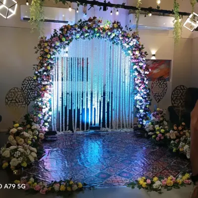 A magnificent entrance arch for a wedding or reception. The arch is covered in colorful flowers and leads to a curtain of white jasmine strings, creating a magical entryway.