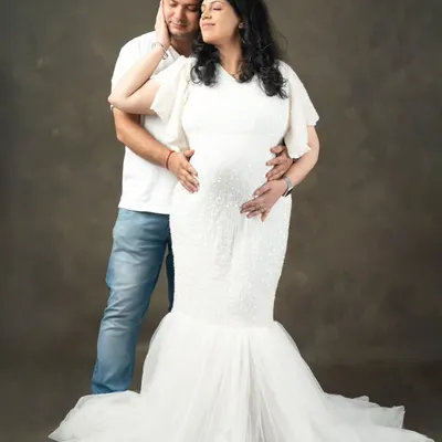 A gentle touch, a quiet moment together. This classic studio portrait against a simple backdrop focuses on the deep connection between you and your partner during this special time.