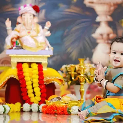 Pure joy and devotion. A toddler in a traditional saree claps her hands in delight during our Ganpati-themed photoshoot, available at our Taloja studio.