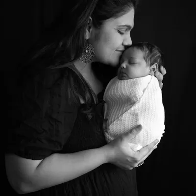 The bond between a mother and her newborn is timeless. This black and white portrait captures the quiet, tender moment of a mother kissing her sleeping baby's forehead, creating an artistic and emotional keepsake.