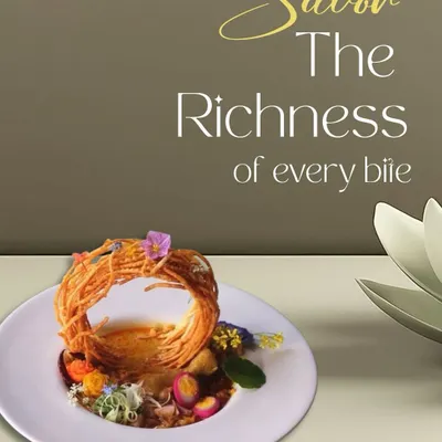 A dish designed to be savored. This plate features a nest of crispy noodles over a rich base, garnished with edible flowers, showcasing our commitment to creating rich, multi-textured culinary experiences.
