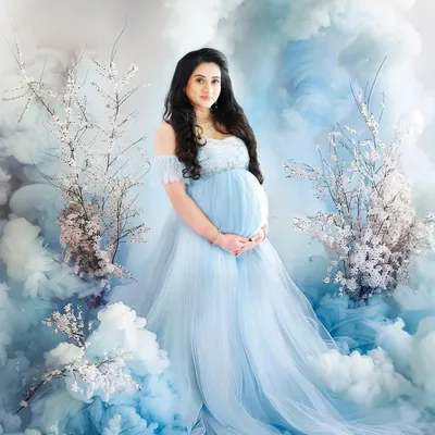 A magical maternity portrait where the mother-to-be is surrounded by a sea of blue clouds and cherry blossoms. She wears a matching light blue gown, creating a truly dreamy and ethereal scene.