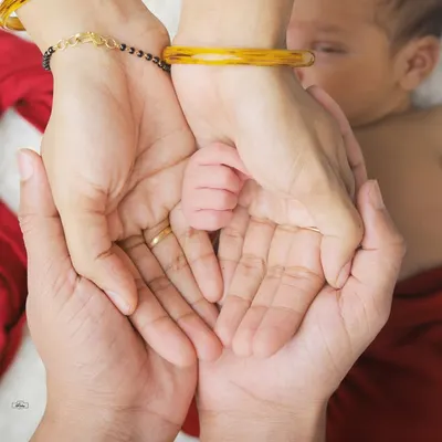 A tiny newborn hand held securely in the loving palms of its parents. This detailed shot is a powerful reminder of how small they once were.