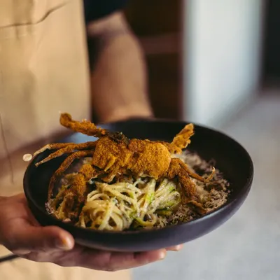 This is where pasta tells a story of the coast. I toss handmade linguine with roasted chili, garlic, and olive oil, then top it with a whole crispy soft-shell crab. It’s a dish that’s both familiar and exciting, bringing a taste of the sea to your table.