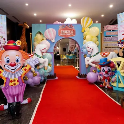 A spectacular grand entrance to a carnival party, featuring a red carpet, clown and animal props, and a personalized archway.