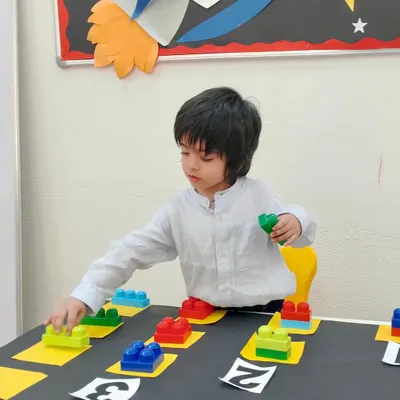 A student carefully places blocks during our "Count and Tell" activity. This hands-on approach to math helps children visualize quantities and connect them to numerals, making abstract concepts concrete.