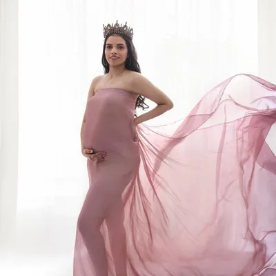 A queen awaiting her heir. This maternity shoot look is all about ethereal beauty, with soft, glowing makeup and a flowing gown to create a truly magical portrait.