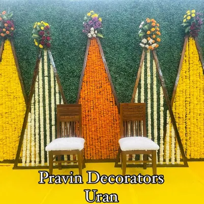 A vibrant Haldi backdrop made with a green foliage wall and geometric panels filled with yellow and orange marigolds. This setup uses fresh, original flowers to bring a traditional and colorful energy to the ceremony.