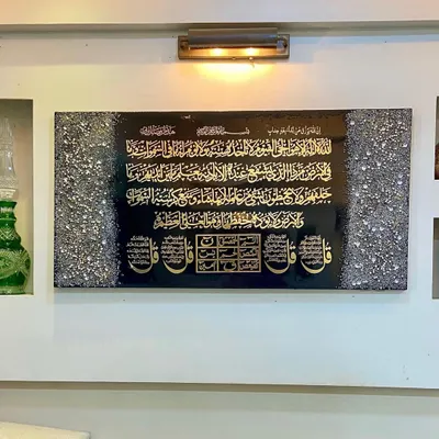 A client's wall featuring a comprehensive art piece. It includes Ayat al-Kursi, the Four Quls, and the Loh e Qurani, all rendered in striking gold calligraphy on a black resin background, framed by textured crystal borders.