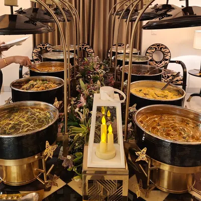 A stunning buffet setup featuring our signature black and gold chafing dishes, elegant floral arrangements, and ambient candle lighting. We design every detail to create a sophisticated and cohesive look for your event.