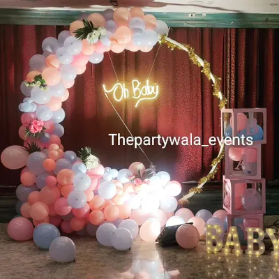 A stunning baby shower setup with a cascade of pastel pink and blue balloons. The 'Oh Baby' neon sign and 'BABY' light-up letters add a perfect touch.