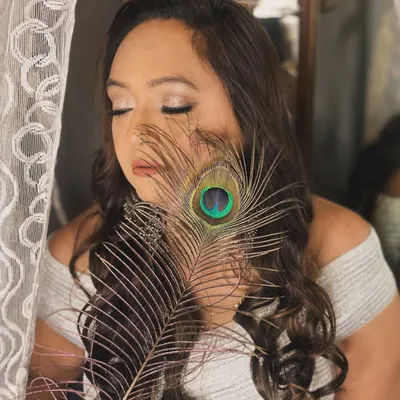 A creative and artistic shot from a portfolio session. The peacock feather adds a touch of mystique to this soft glam makeup look.
