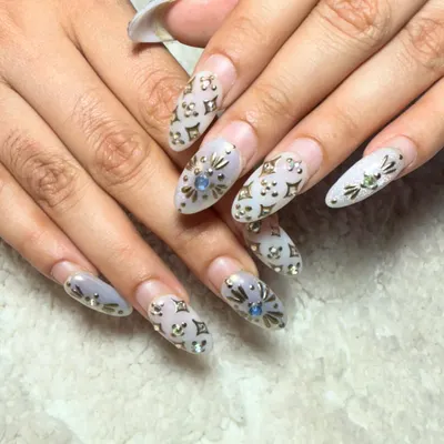 An incredibly detailed and luxurious design. These almond-shaped extensions feature a subtle logo pattern with carefully placed gold and blue rhinestones for a high-fashion look.