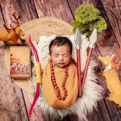 A tribute to the epic Ramayana, this unique setup features a newborn dressed as a young sage, complete with a rudraksha necklace. The scene is adorned with a bow, arrows, and deer, evoking a sense of ancient adventure.