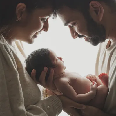 A family born in one magical moment. This intimate portrait captures the awe and love as new parents gaze at their baby, held securely in their hands.