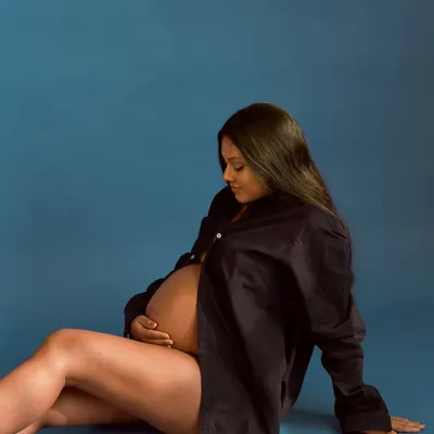 A quiet and intimate moment from a maternity session. The simple styling with an open shirt creates a raw and beautiful portrait, celebrating the natural form of pregnancy.