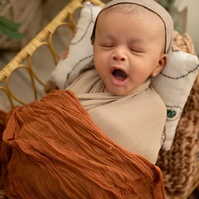 A big sleepy yawn! I love catching these candid moments. This little one is tucked into a wicker basket with soft blankets, perfectly safe and cozy for a nap.