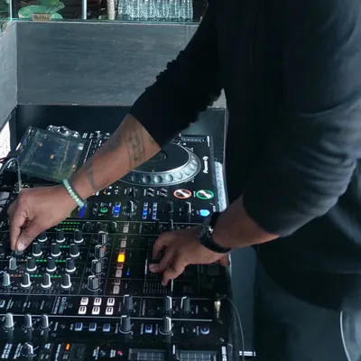 A close-up shot of my hands on the Pioneer DJ mixer. This is where the magic happens, as I blend tracks, control levels, and add effects to create a seamless musical journey.