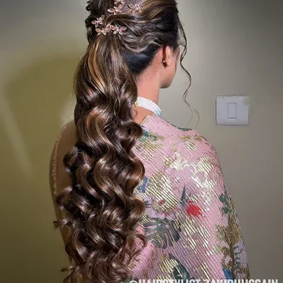 A glamorous ponytail with voluminous curls and a twisted crown, adorned with delicate floral clips. This style is perfect for adding a touch of elegance to a modern outfit.