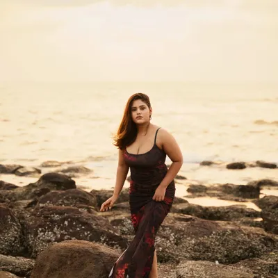 A full-length portrait during a beach photoshoot, with the wind adding natural movement to the dress. The focus here is on creating a relaxed pose that feels connected to the seaside environment.