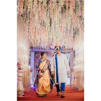 The grand walk as husband and wife. The couple walks hand in hand under a beautiful floral canopy, a perfect moment captured from their Maharashtrian wedding ceremony.