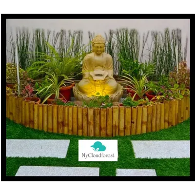 This is a serene corner I designed, featuring a gently flowing Buddha water fountain as the centerpiece. The installation is set on artificial grass, enclosed by a bamboo-style border, and includes white stone pavers for a clean, contemplative path.