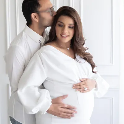 A tender moment from an all-white maternity session. I guide couples into poses that feel natural and loving, capturing the quiet intimacy before the baby arrives.