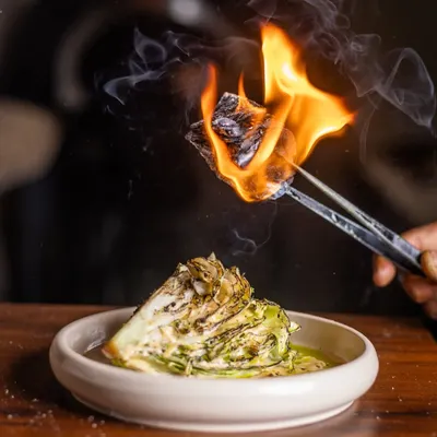 I like to add a little theater to my dishes. The Manor Caesar salad gets a smoky twist from a piece of burning charcoal, infusing the crisp lettuce with a unique, aromatic flavor right at your table.
