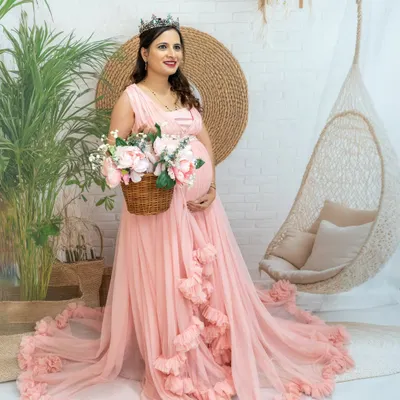 A beautiful princess-style portrait in our boho studio setup. The mom-to-be looks radiant in a pink gown and tiara, holding a basket of flowers.