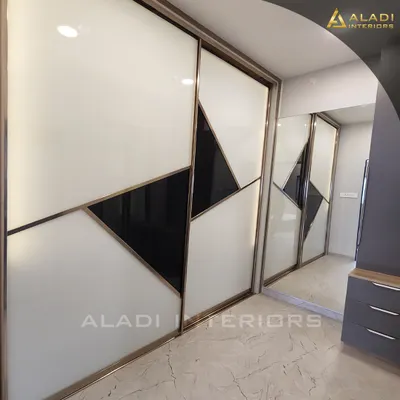 A modern sliding wardrobe with a striking geometric pattern in black and white glass, framed with a gold finish. This piece is both a functional storage unit and a bold design statement.