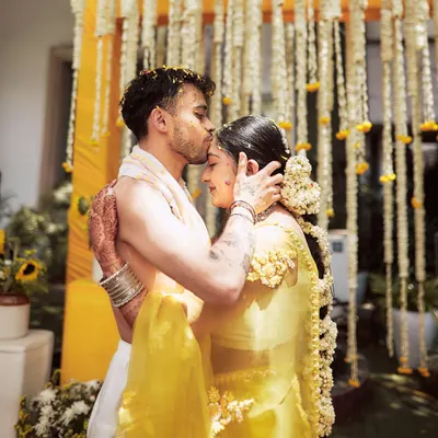 An intimate and emotional moment between the couple during their Haldi ceremony. The backdrop of hanging jasmine and marigold strings provides a traditional and fragrant setting for these beautiful memories.