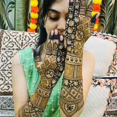 A playful pose showing off a beautiful bridal design that incorporates the couple's initials, "KR" and "AS," inside elegant circular frames on the palms.