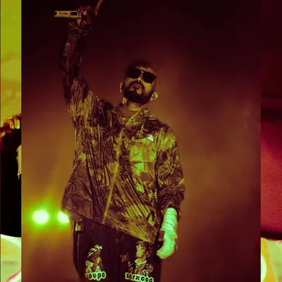 Calm from Seedhe Maut commands the stage in Bangalore, pointing to the sky. The yellow and red lighting creates a fiery mood that matches the intensity of their performance.