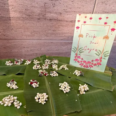 A charming "Pick Your Gajra" station is a wonderful traditional touch for any Indian celebration. Here, fresh jasmine gajras are beautifully displayed on banana leaves with a custom-designed sign, inviting guests to adorn themselves with fragrant flowers.