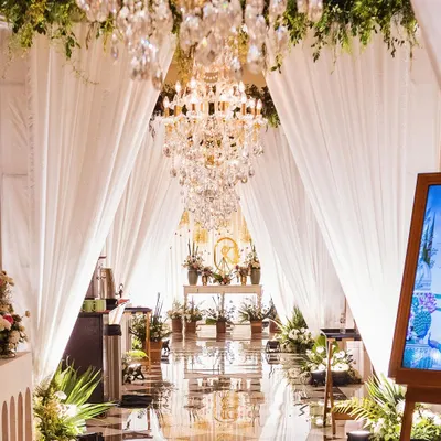 A breathtaking entrance gallery for a Mehendi, with a reflective floor, cascading chandeliers, and lush greenery. I design these immersive pathways to wow your guests from the moment they arrive.