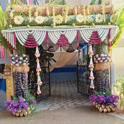A full front view of an elaborate and traditional entrance decoration, perfect for a housewarming. The design uses sugarcane, banana leaves, coconut shells, and extensive floral work to create a grand and auspicious welcome.