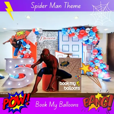 Your friendly neighborhood Spider-Man swings in to save the party. This setup for Dhruva's 5th birthday features a city backdrop, comic book-style props, and a large light-up number '5' that Spidey is perched on.