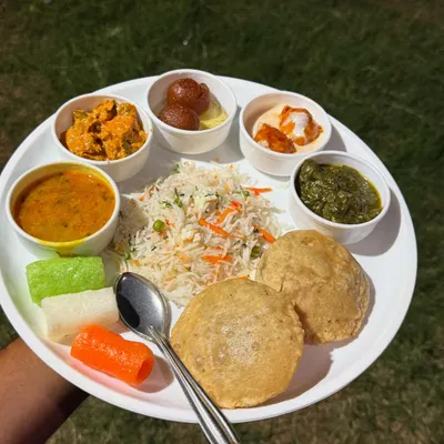 A beautifully plated Jain thali to showcase the quality and variety you can expect. This meal includes vegetable pulao, puris, dal, a rich paneer sabzi, green chutney, and gulab jamun for a complete dining experience.