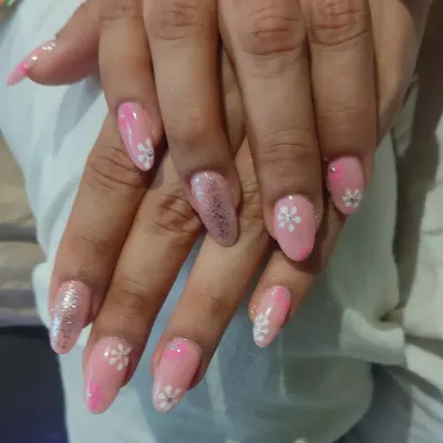A sweet and feminine design featuring a soft pink base with hand-painted white daisy flowers and a single glitter accent nail.
